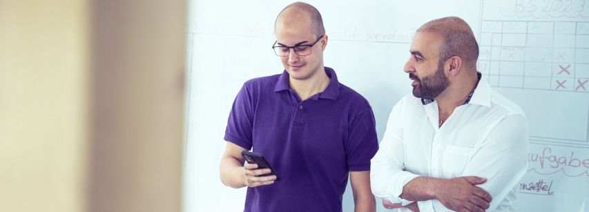 Zwei Mitarbeiter unterhalten sich am Whiteboard