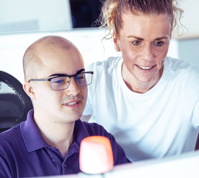 Ein Mann und eine Frau schauen den Bildschirm an